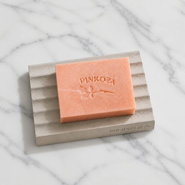 PINKOZA Imperial Topaz handmade pink goat milk soap bar resting on a PINKOZA ribbed grey soap dish