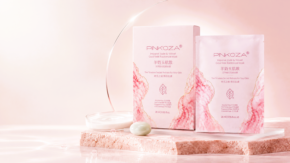 PINKOZA Imperial Jade and Velvet Goat Milk Radiance Mask five pack box next to a single sachet on a pink stone slab with a glass dish of skin care cream.