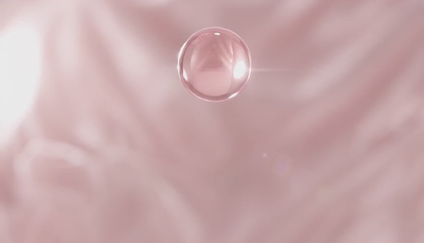 PINKOZA brand reveal video featuring a soft pink silk background, a blurred pink rose, a pink crystal, and a clear water droplet splashing in front of the PINKOZA logo.